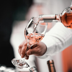 The waiter serves rose, red and white wine from the wine bottle in the wine glass at an event. - 440413675
