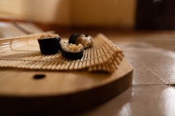 Three slices of homemade sushi served on woven bamboo and wooden mats.
