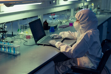 Female researcher in wheelchair looking at laptop display while working in scientific laboratory