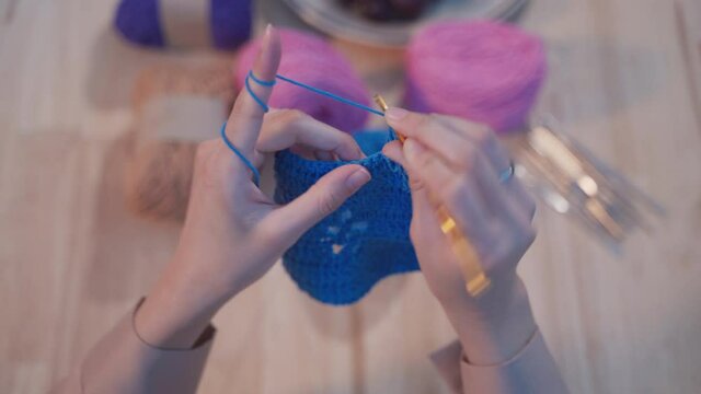 Young adult Asian woman doing hobby by sewing and knitting a crochet handmade in living room at night by learning and study from internet using laptop. New normal lifestyles working at home concept