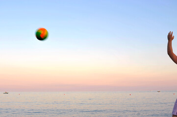 Young men playing handball on the shore as the afterglow of sunset towers above the horizon.