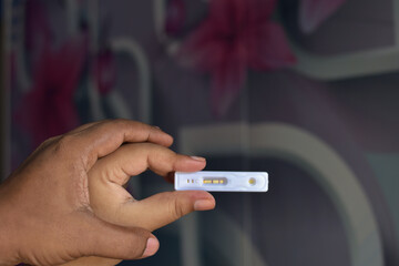 Happy woman and her husband holding pregnancy kit with a positive result at home. they creat a love sign with thair hand close up.