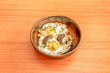 bowl of fried eggs with truffle sauce and chips and chives