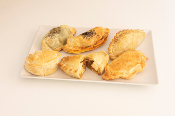 Argentine empanadas made with puff pastry flour and one of them cut in half to show the meat and cheese filling