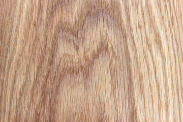 An oak kitchen chopping board covered in knife scratches. Uneven texture of a polished board with a pattern and streaks of natural wood.