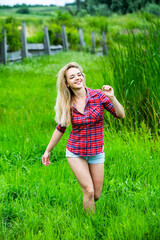 The blonde girl is having fun in the river in rubber boots in the country. Young woman on a lake enjoy the life.