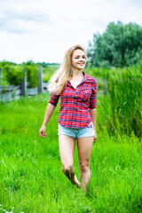 The blonde girl is having fun in the river in rubber boots in the country. Young woman on a lake enjoy the life.