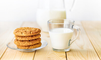 A glass of milk with cookies on a wooden table.