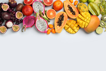 Many different delicious exotic fruits on light background, flat lay. Space for text