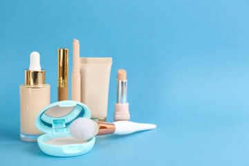 Foundation makeup products on light blue background, space for text. Decorative cosmetics