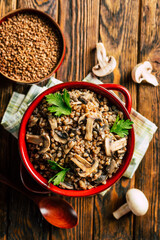 buckwheat porridge with mushrooms in a ceramic pot on a wooden background
