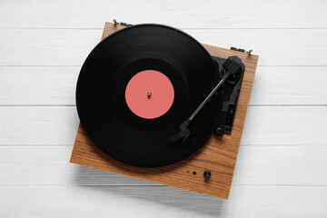 Turntable with vinyl record on white wooden background, top view