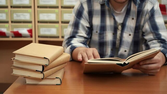 A man reads a book in the library sitting at the table