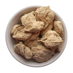 Dehydrated soy meat chunks in bowl on white background, top view
