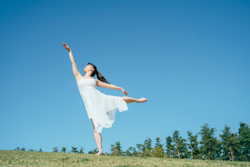 空と白いワンピースの踊る女性（アラベスク）
