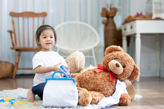 A happy asian girl smiling and lying on the floor with playing teddy bear
