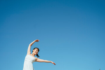  空と白いワンピースの踊る女性