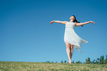 空と白いワンピースの踊る女性（深呼吸・全身）
