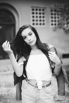 Beautiful young woman posing in front of apartment building dressed casually