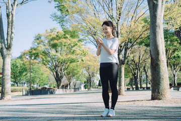 公園でスポーツしながら電話する女性
