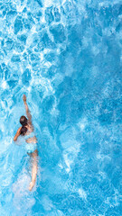 Active girl in swimming pool aerial drone view from above, young woman swims in blue water,...