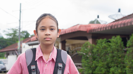 Portrait Asian high school girl in uniform with backpack wears earphones posing and looking at camera. - 440427058