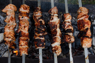 Shish kebab in the open air cooking process. The fried meat on the skewers is almost done. Coals in the grill