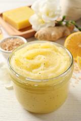 Body scrub in glass jar on white wooden table, closeup