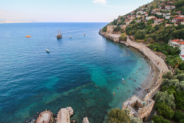 The historical Kızıl Kule (Red Tower), castle wall and ruins of the historic harbor of Alanya beach, Top view to the shipyard and mediterranean sea.