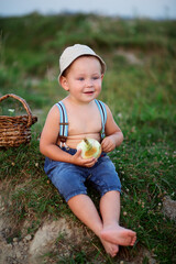 A little boy in a hat is fishing in the lake on a summer evening, peeling an onion for fish soup 