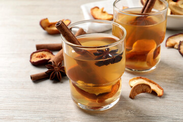 Delicious compote with dried apple slices, anise and cinnamon on white wooden table