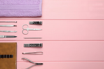 Set of manicure tools, towel and case on pink wooden background, flat lay. Space for text