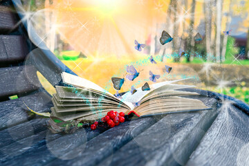 Fairy tale butterflies fly from a magic book lying on an old wooden bench in the park. Fantastic...