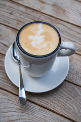 cup with a cappuccino on a wooden table. Delicious coffee