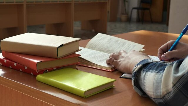 A man leads entries in a notebook sitting at the table in the office
