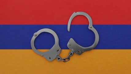 A half opened steel handcuff in center on top of the national flag of Armenia