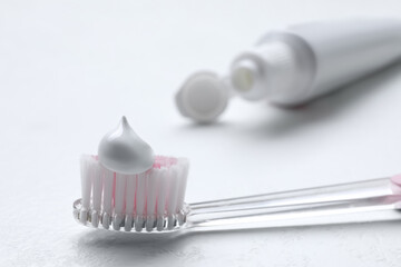 Brush with toothpaste and tube on white background, closeup