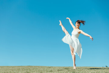 Obraz premium 空と白いワンピースの踊る女性（アラベスク）