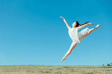 空と白いワンピースの踊る女性（ジャンプ）
