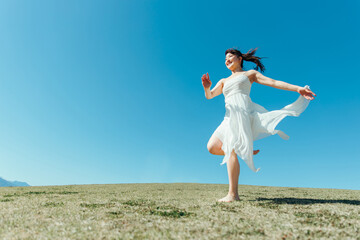 空と白いワンピースの走る女性
