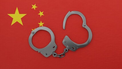 A half opened steel handcuff in center on top of the national flag of China