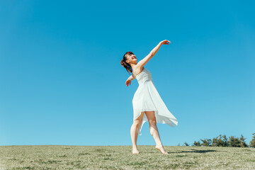 空と白いワンピースの踊る女性

