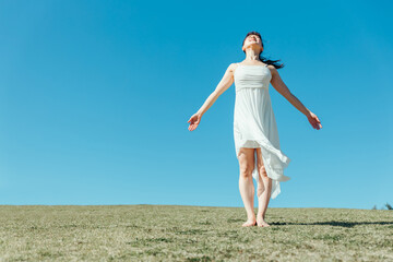 空と白いワンピースの踊る女性（深呼吸）