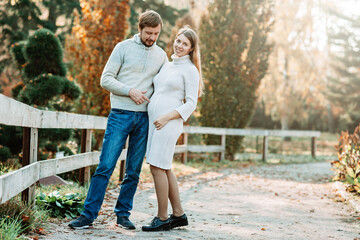 Family together in autumn park. Happy couple Husband and his pregnant wife relaxing in nature. happy married couple expecting baby. Pregnancy, maternity concept. Parents hands on pregnant belly