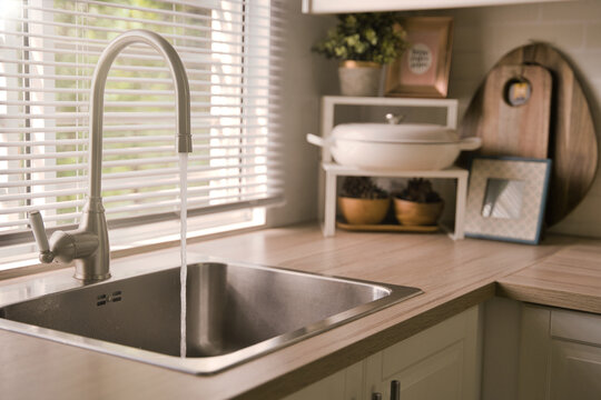 Water running from the tap into a kitchen sink. Clean and drinking water. Save water and enviromental concept.