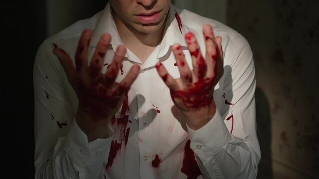 Scared man looks at his bloody hands
