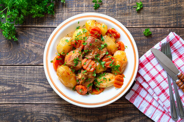Roast turkey, potatoes, carrots and fresh parsley in a bowl on a wooden background. Useful and nutritious dish. Top view.