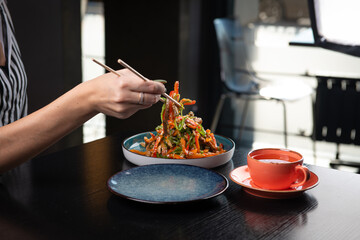 Girl takes salad from plate with sticks