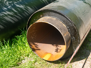 Noyabrsk, Russia - June 5, 2021: New large iron sewer pipes lie on the ground. Black pipes lie on...