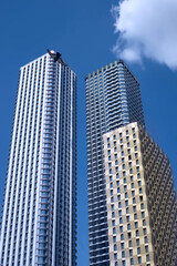 Fototapeta premium Two modern tall buildings, skyscrapers in the blue sky.